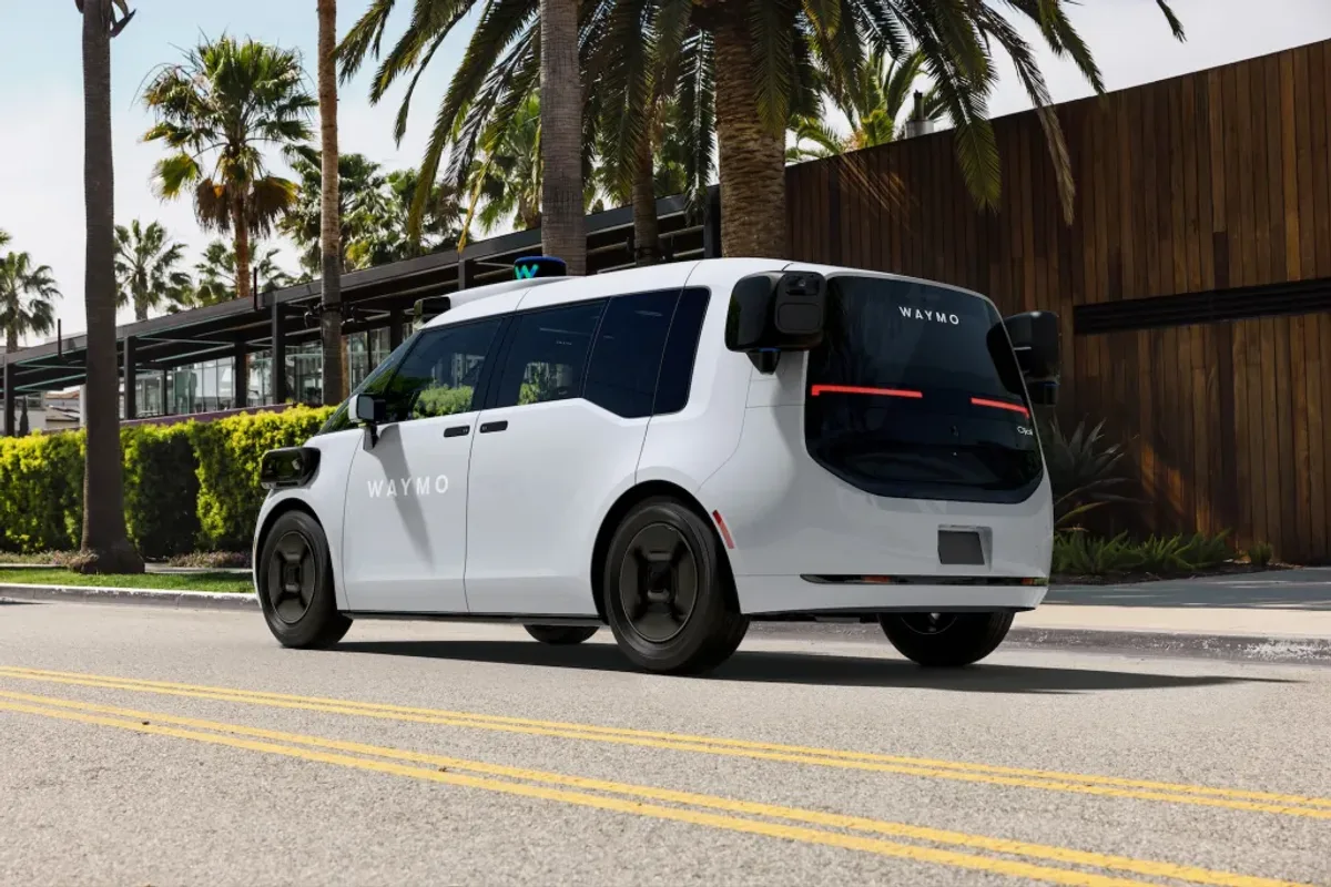 Robotaxi Waymo Ojai circulant dans une rue bordée de palmiers, photographie officielle illustrant la flotte autonome